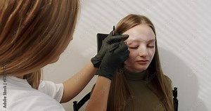 Cosmetologist marks the lines with a special thread to create the correct shape of the eyebrows during permanent makeup process. making eyebrow permanent makeup. Work of master cosmetologist.