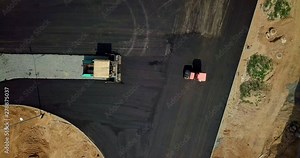Aerial view on the new asphalt road under construction. Road works with steamroller machine and asphalt finisher. Yellow road repair machine. Repairing in modern city with vibration roller compactor.