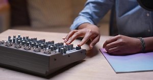 Young multiracial woman is using microphone in recording studio while adjusting sound mixing equipment and smiling. Modern technology, profession and youth concept