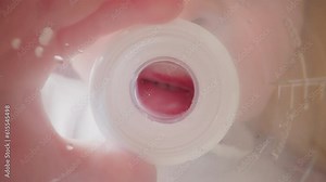 Child holds plastic bottle. Kid mouth clamps and unclasps nipple blowing out bubbles into water. Thirsty boy drinks liquid at home macro low angle shot