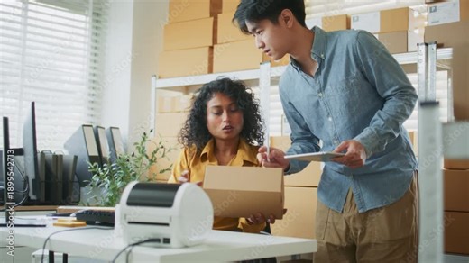 Team reviews shipment status on a Computer while managing packing desk tasks, connecting digital tracking with physical packaging for Dispatch. Team Discussion During Shipping Preparation.