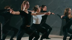 Gorgeous slim actress rehearsing with colleagues as stage director adjusting positions. Portrait of concentrated Caucasian young woman looking away squatting stretching hands