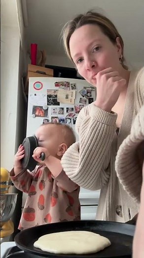 Toddler excitedly flips pancake while cooking breakfast in Moscow, Russia
