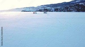 Winter fishing on the snow-covered lake Baikal against the background of rocks and hills. A frosty sunny day Stock Video
