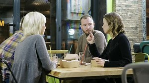 Two beautiful women and two men eating delicious food, drinking soft drinks and chatting in the modern restaurant. 4K
