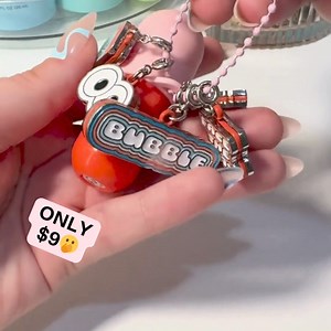 Smoochable softness is just a swipe away! The new Tell All Juicy Secret Berry Lip Balm hydrates and plumps your lips, leaving them irresistibly soft and smooth. Plus, it comes with a matching keychain, so your ride-or-dry bestie is always with you! Shop now and customize with collectible Bubble Charms! 💋✨ | Bubble