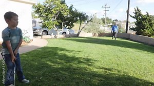 Young boy practicing his golf swing in the front yard with his father.