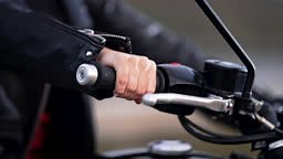 Female motorcyclist hand twists accelerometer lever while standing at...