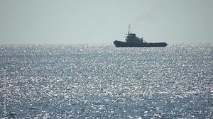 Tug boat in open calm sea, heading back to port at sunset, helps large container ships maneuver. Aerial view, maritime industry, oceanic transportation or business concepts.