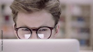 Young, healthy and attractive student boy is working with his laptop. Man is connected online and surf the web. He is reading screen, typing on the keyboard.