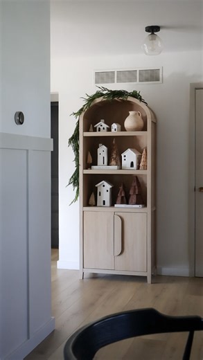 Crystal Hanson on Instagram: "How I styled my arched bookcase for Christmas ✨🎄 simple houses with twinkle lights, trees and Norfolk pine garland draped over the top Comment shop and I’ll send you the links ✨"