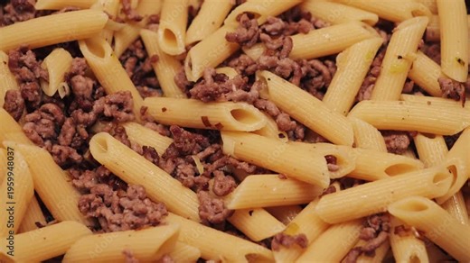 Penne pasta with ground beef, freshly cooked and served as a hearty homemade meal. Close-up of pasta mixed with savory meat. High quality 4k footage