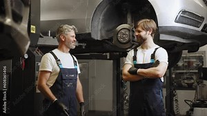 Funny mechanical engineering joking in car repair shop or garage. Workflow in a car workshop. Father working with his son. Family business concept. Workflow in a car workshop. Mechanic in work.
