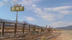 Time lapse and slow zoom shot of clouds drifting past a sign saying eat at an abandoned diner.