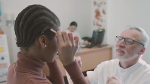 Free stock video - An ophthalmologist fits special optometry glasses on a young girl patient in his clinic for a vision test