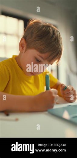 A young boy focuses on his drawing and writing tasks at a table. He uses markers and shows interest in his work. The light creates a warm atmosphere as he concentrates Stock Video Footage - Alamy