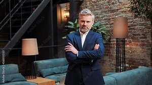 Handsome successful businessman with a beard is looking to camera while folding hands. Financial expert, lawyer, banker leader posing in the negotiation room. Headshot business male serious portrait.