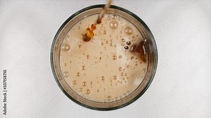 The coke pours into the glass. Foam on top of the drink and air bubbles inside. The theme of food and drink.