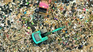 Garbage piles are cleared by workers who operate excavators to scoop waste into trucks for transport to landfills. This process ensures proper waste management. Ecological problem concept. 4K