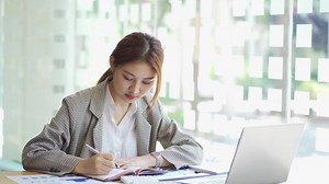Femme d'affaires utilisant la calculatrice pour effectuer des opérations mathématiques sur un bureau en bois et sur le fond de travail d'entreprise, fiscalité, comptabilité, statistiques et concept de recherche analytique.