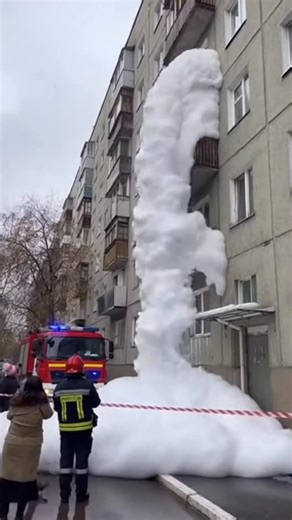 Anatolii Marynyuk on Instagram: "The washing machine malfunctions and suddenly releases an overwhelming wave of foam. It pushes out through every opening, spilling from the balcony and flooding the stairwell inside a multi-story building. The foam spreads rapidly across shared areas, covering everything in sight. Firefighters and police respond to the incident, but the situation remains difficult to control. This text and video are entirely fictional and created using artificial intelligence."
