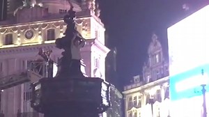 Man climbs up Eros statue in Piccadilly Circus