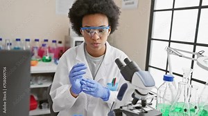 A focused woman scientist in a laboratory, wearing a lab coat and protective eyewear while conducting research.