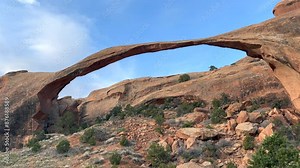 Static shot of the Landscape Arch, one of the longest natural stone arches in the world, in Arches National Park, Utah. The red rocks contrast beautifully with the bright blue sky - USA