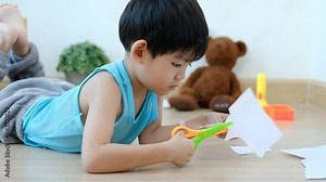 Asian boy using scissors to cut paper along lines Learning outside the classroom