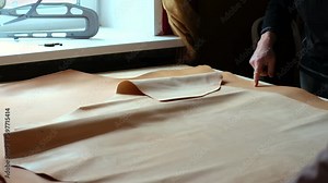 skilled artisan displays a roll of natural leather, demonstrating the high-quality tanning techniques used in creating bespoke leather products. Leather Craftsmanship: A Timeless Tradition