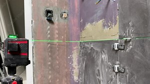 Modern construction laser level on construction site for precise measuring, construction device showing green rays crosshair for taking accurate measurements