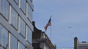 The U.S. flag waving on a building roof and a plane passing in the distance.