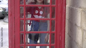 Classic red telephone booth. A girl inside a telephone booth.