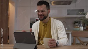 One man use digital tablet have video call online and hold cup at home