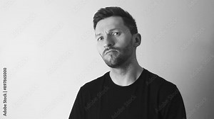 Footage of a man doing a nod and a nodding expression of approval in slow motion shot in 4K resolution. The expression means yes, you can do it and is shot in black and white by a tattooed man.