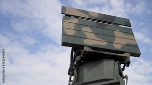 Military combat radar in army paint, with clear cloudy sky in the background (slow motion)