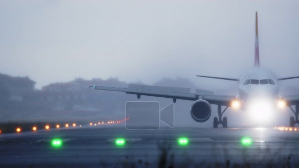 A commercial airplane with bright landing lights on approaches and touches down on an illuminated runway. The scene is shrouded in dense fog, creating a dramatic and low visibility atmosphere Stock Video Footage - Alamy