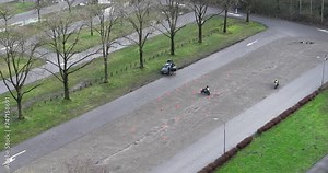 Motorcycle driving lessons, traffic cones, instructor and students. Teaching and building expereince on a mtorcycle on an empty parking space. Aerial birds eye view.