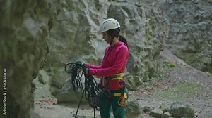 Young professional female climber hiking in the forest. Fit active woman adjusting safety ropes on the cliff. Preparation. Climbing concept. Stock Video