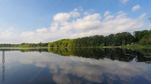Beautiful lake and sky time lapse with clouds, forest reflections and boat rental marina on glassy water in Heart lake Conservation Area, Brampton, Ontario, Canada