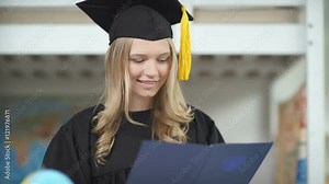 A graduate in the Master's cap and gown. A graduate holding a diploma of higher education and smiling. Graduation. High school graduation. Diploma of Higher Education of the Russian sample.