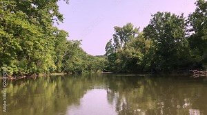 Kayaking and walking through a river and lake with stones and greenery all over. Serene nature shots with boaters and a forest.