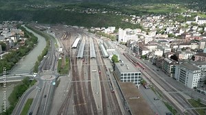 A train enters the main station of Brig. In the background is the town of Brig and Naters. Aerial Shot