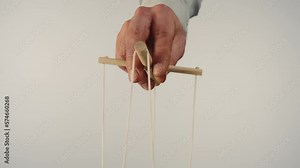 The puppeteer's hand controls the puppet with a wooden manipulator and strings. The marionettist controls and pulls the strings on a white isolated background. Close up.