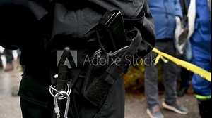 Police officer's belt with a gun and baton tonfa. Policeman standing on the street during protest. Policeman carrying pistol weapon in holster on demonstration.
