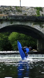 Kayak freestyle tricks under the old stone bridge