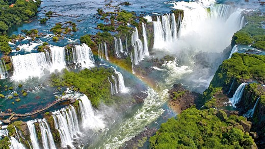 Giant waterfalls forming rainbows over a deep canyon