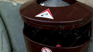 Metal trash bin with a no smoking hazard sign, tilt close down shot