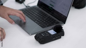 Professional Editor Syncing Audio Recorder With Laptop. Audiovisual Specialist Preparing Digital Recorder Setup