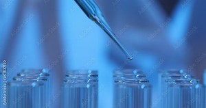 Drop of liquid falling from a pipette into test tube in laboratory